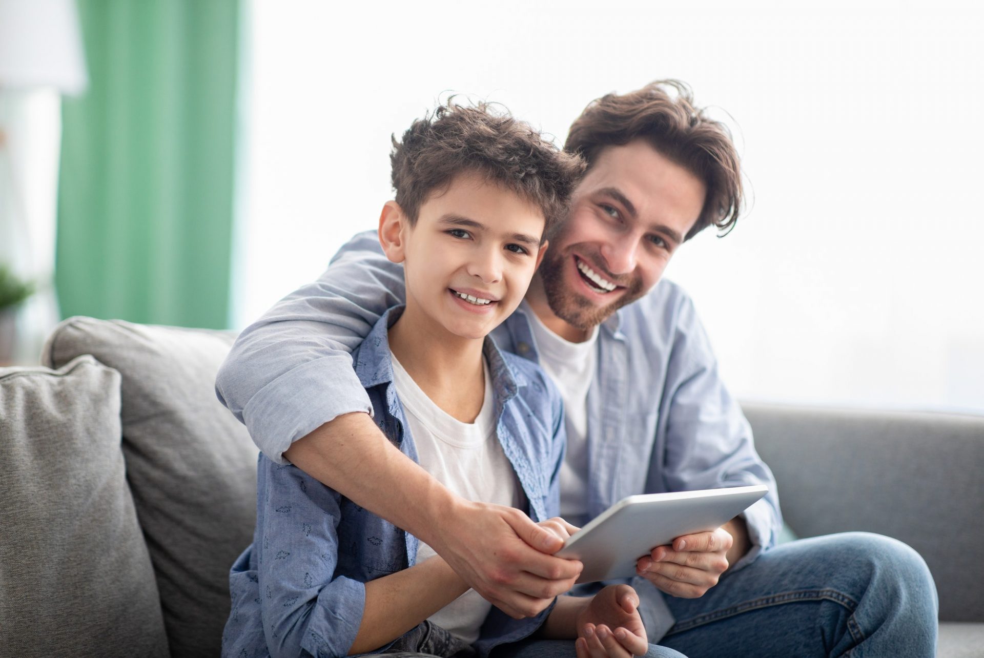 family-time-happy-dad-and-son-using-digital-tablet-browsing-internet-online-at-home-sitting-e1632233068896.jpg